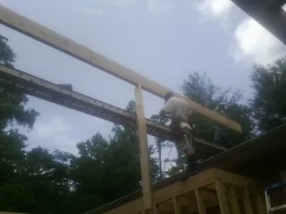 Carpenter setting a ridge beam over a new addition frame — Ice Dam Removal by Roofing Brothers in Tensed