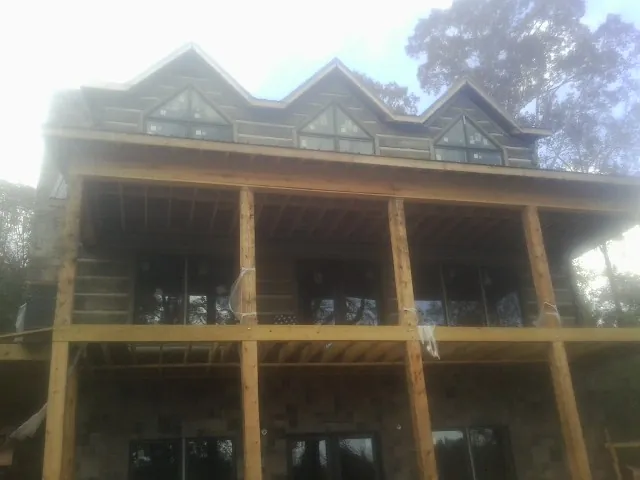 Dormers and porch framing on a large log home under construction — Roof Coating work by our crew in Tensed