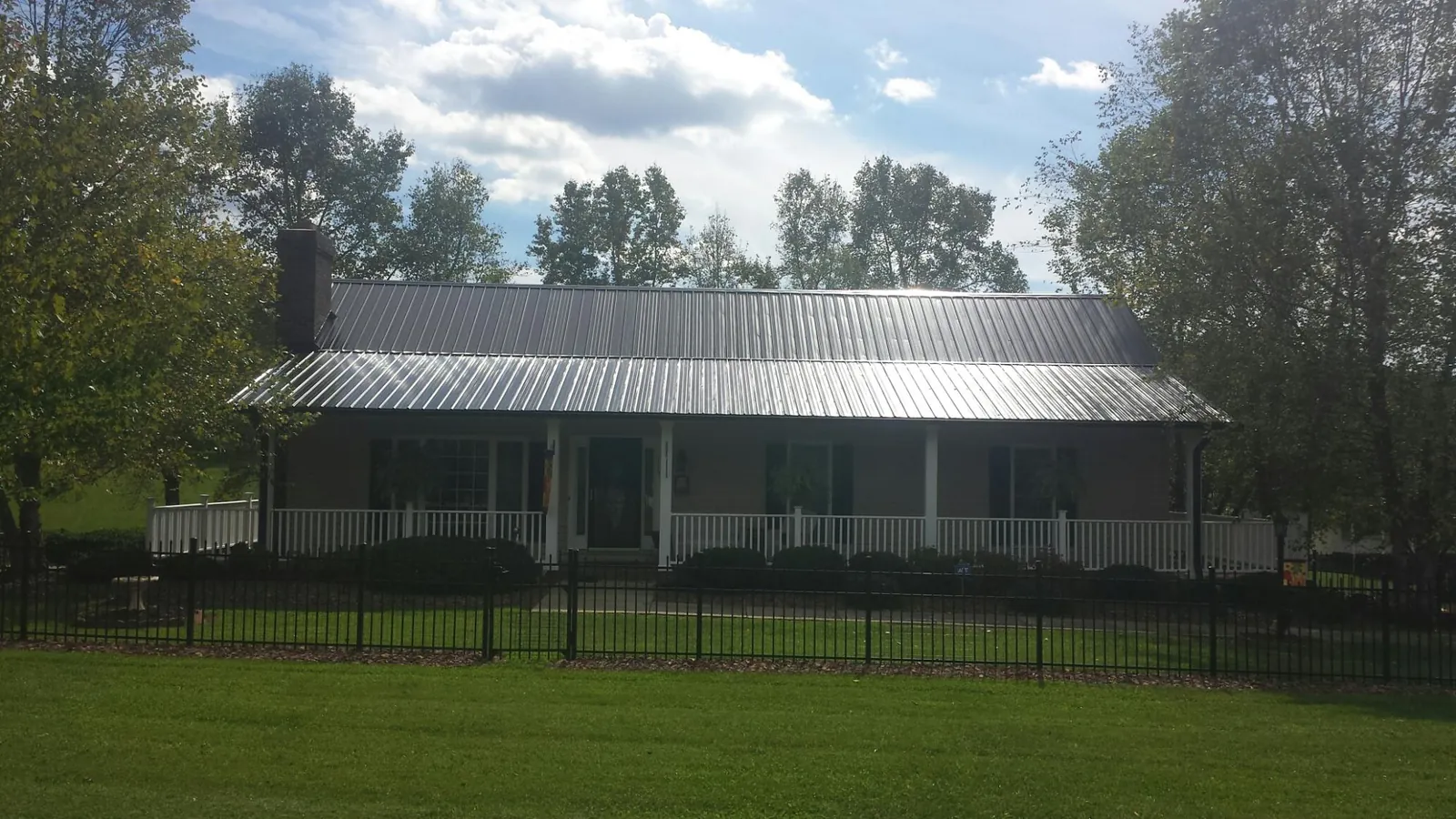 Gray metal roof on a brick ranch with a full width front porch — Gutter Guard Installation work by our crew in Tensed