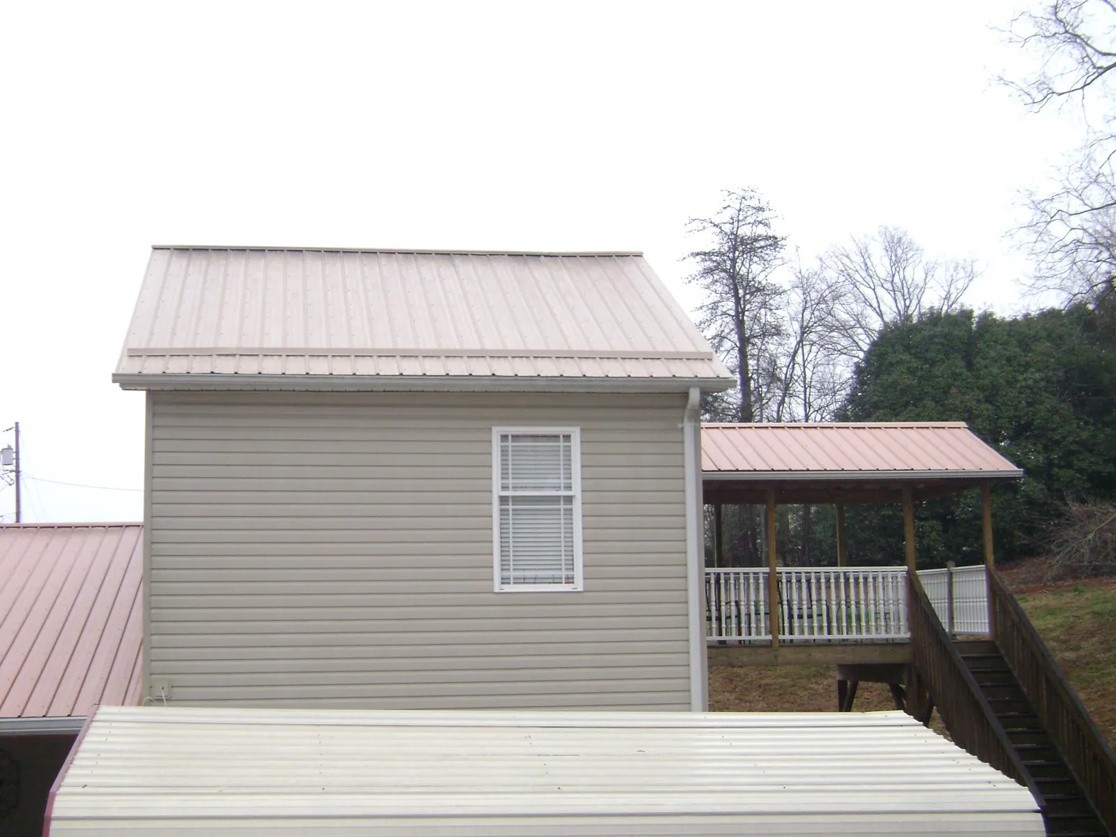 Tan metal roofs on a two story addition and attached porch, from a Roof Replacement job in Tensed