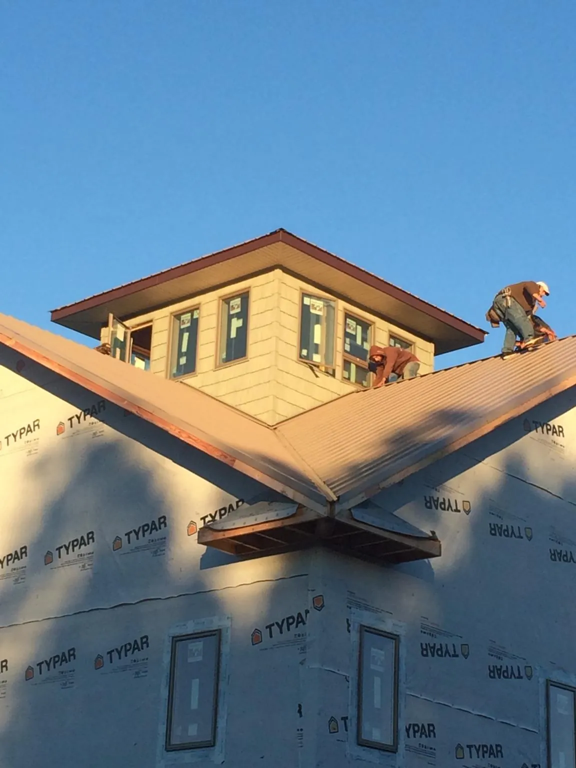 Roofers working around a rooftop cupola on a new metal roof at sunset — Roof Waterproofing in Tensed by Roofing Brothers